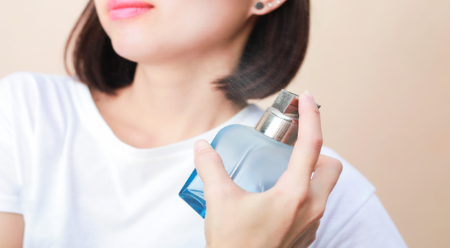 Seseorang menyemprotkan parfum pada tubuh

